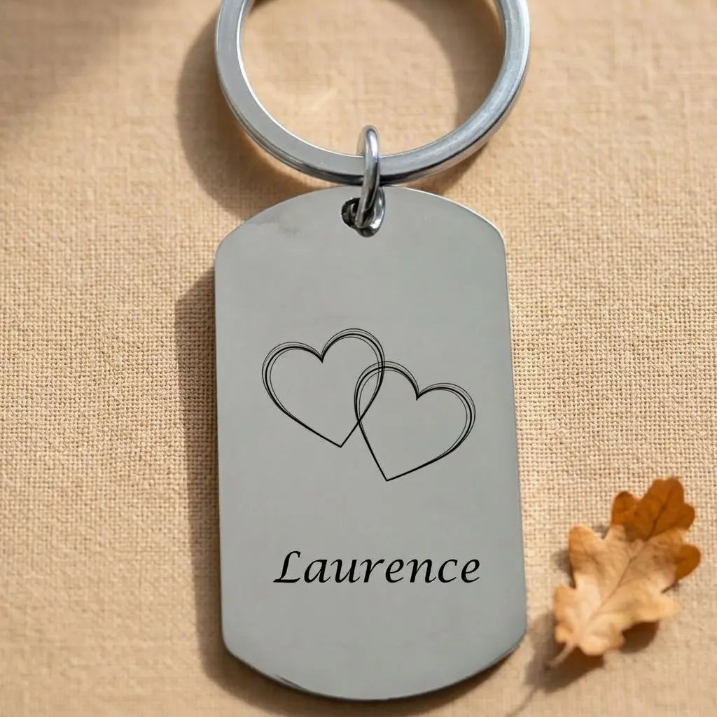 Porte-clés personnalisé en métal avec deux cœurs dessinés et le prénom Laurence gravé en bas.